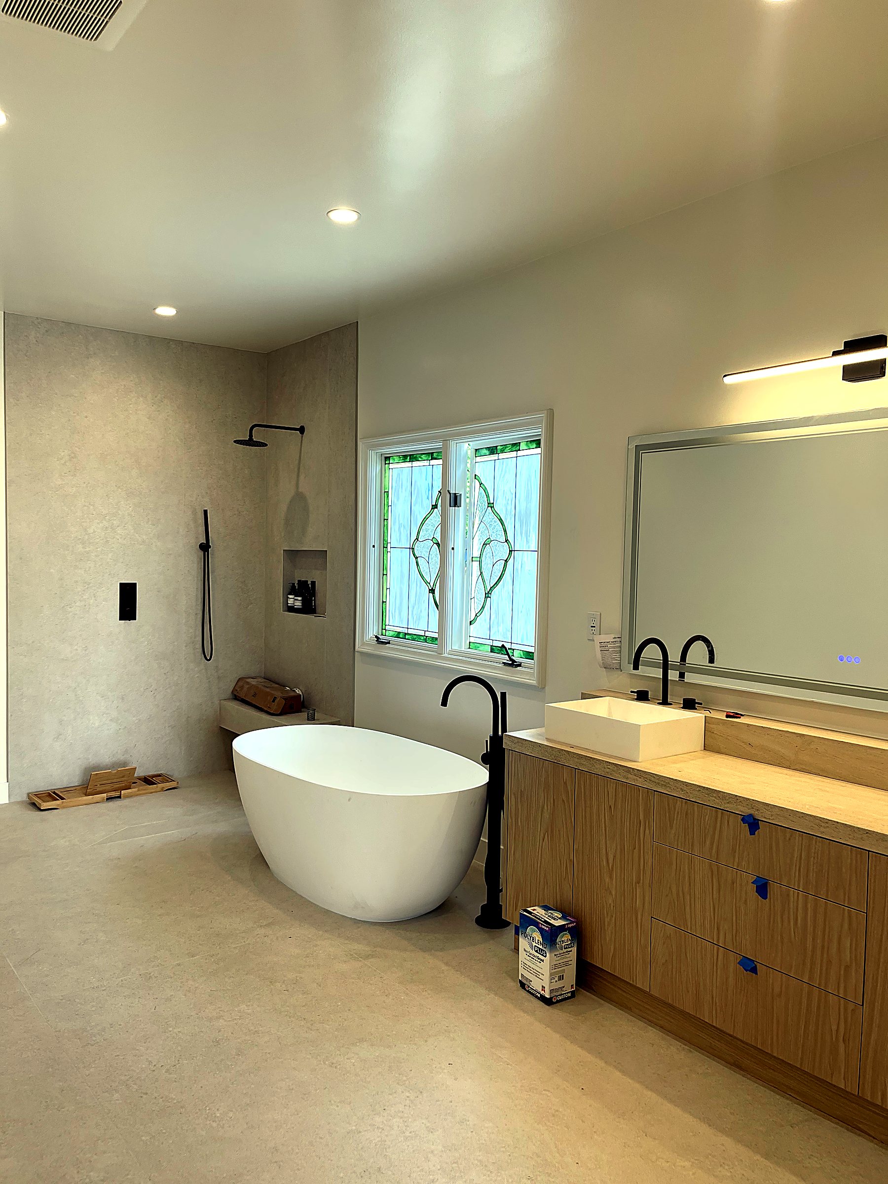 Finished primary bathroom with freestanding tub and oak vanity